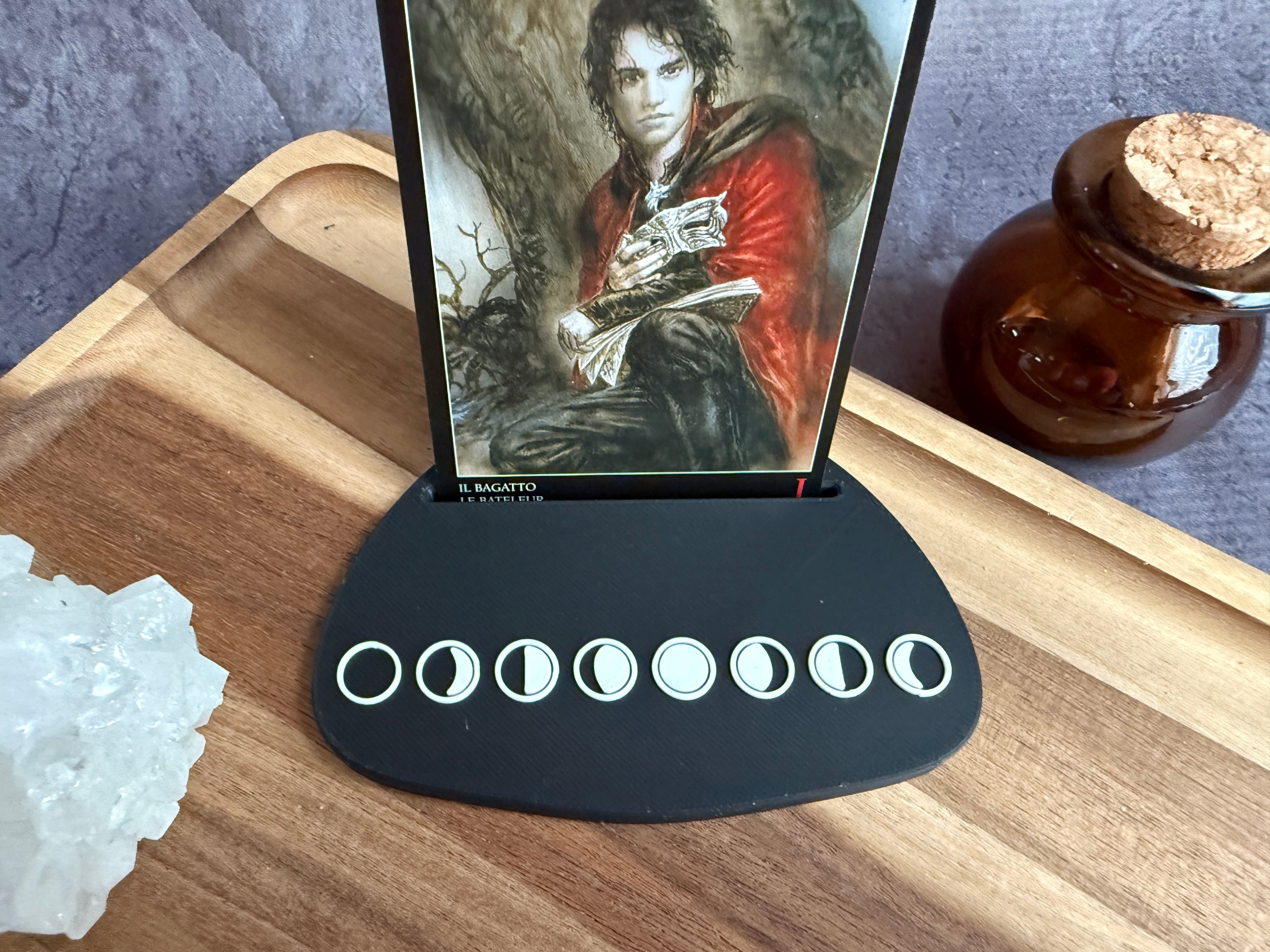 Tarot card holder with a card in it with character illustration all on a wooden surface