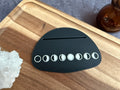 Black moon phase Tarot card holder on a wooden surface