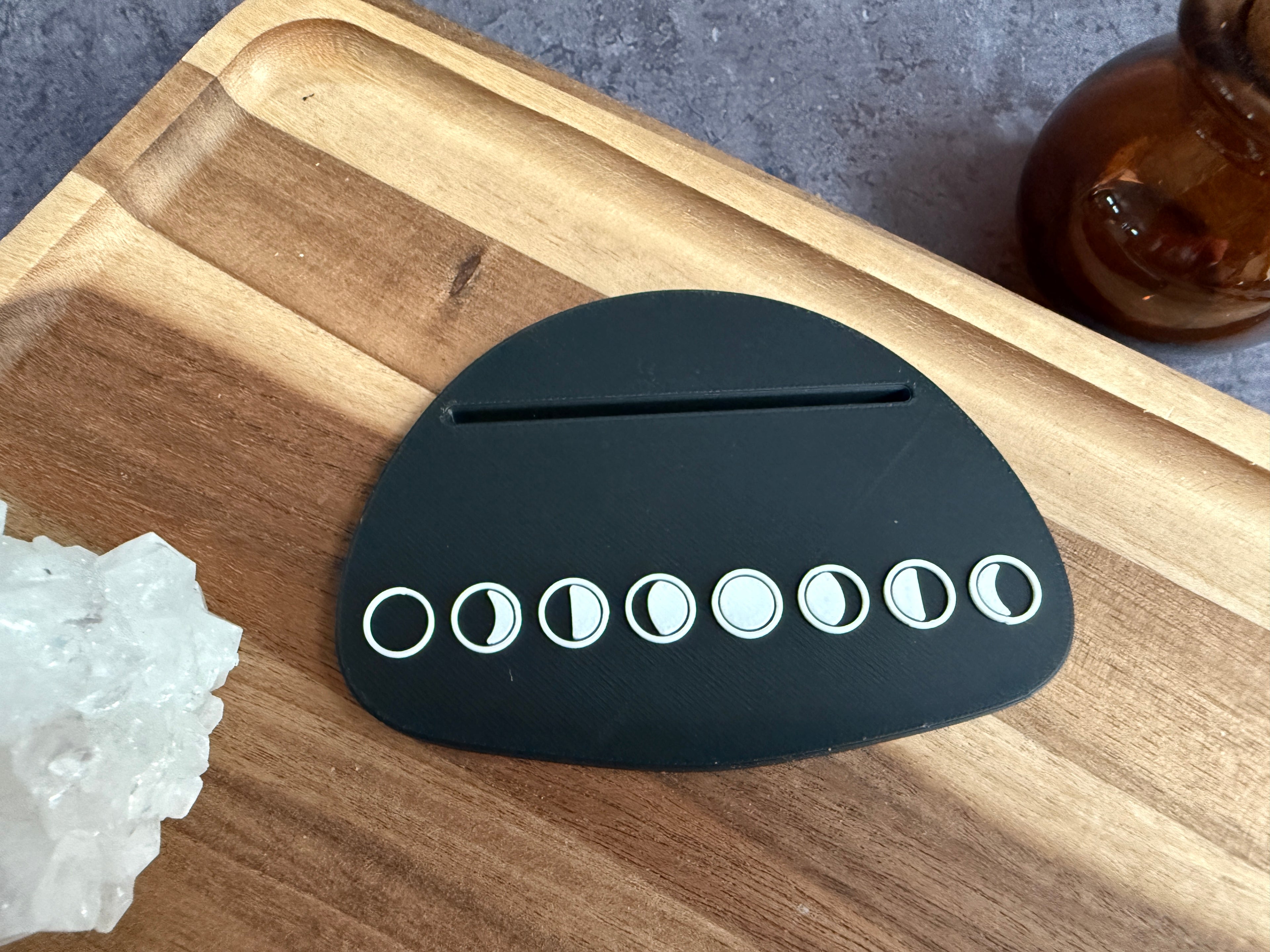 Black moon phase Tarot card holder on a wooden surface