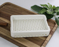 White 3D printed soap dish on a wooden cutting board with cinnamon sticks and green leaves in the background