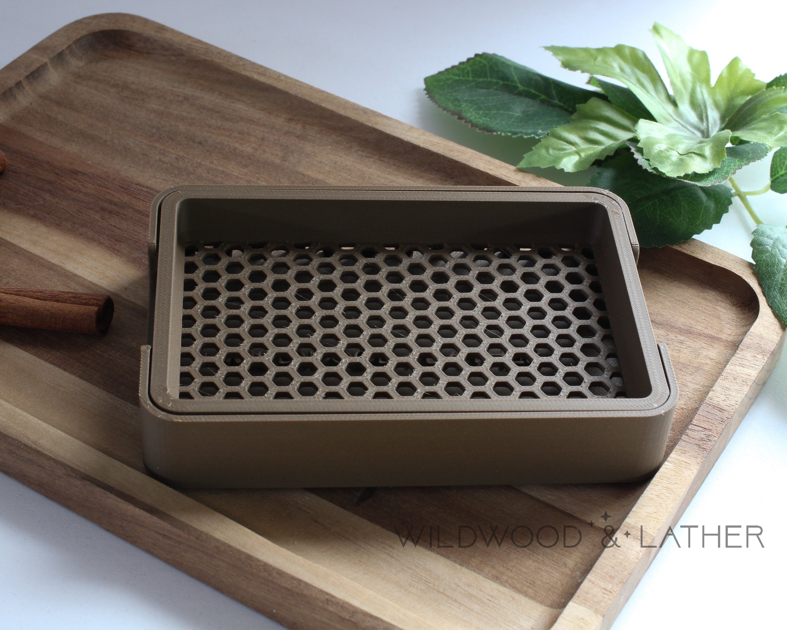 Dark Brown 3D printed soap dish on a wooden cutting board with cinnamon sticks and green leaves in the background